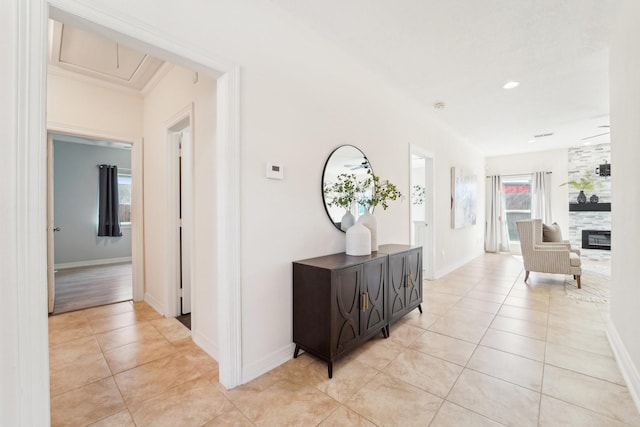 hallway featuring attic access, light tile patterned flooring, and baseboards