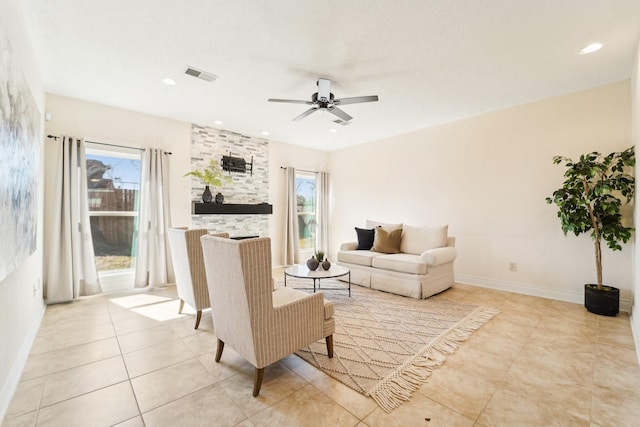 living room featuring ceiling fan, a fireplace, visible vents, and a wealth of natural light