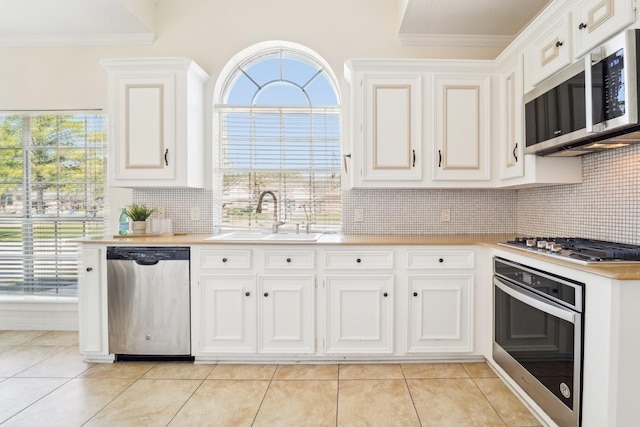 kitchen featuring crown molding, light countertops, appliances with stainless steel finishes, white cabinets, and a sink