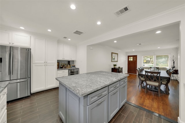 1931 Ansbury Dr, Houston, TX 77018 - kitchen featuring wood finish floors, recessed lighting, visible vents, freestanding refrigerator, and white cabinets