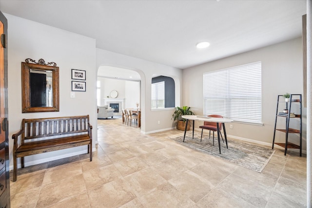 dining space featuring arched walkways, a fireplace, and baseboards