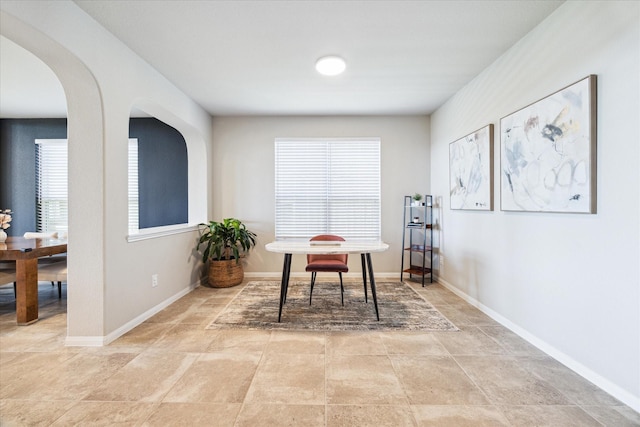 interior space with baseboards and arched walkways