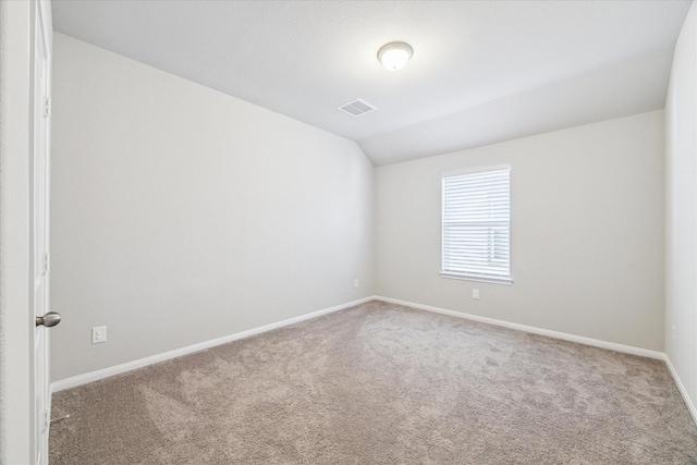 empty room featuring lofted ceiling, baseboards, visible vents, and carpet flooring