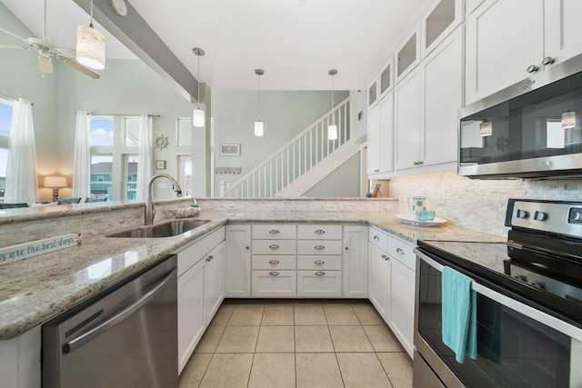 kitchen featuring stainless steel appliances, white cabinets, light tile patterned flooring, and a sink