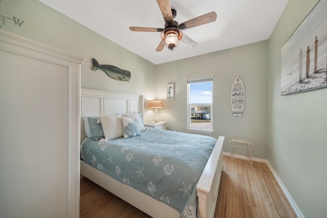 bedroom with ceiling fan, baseboards, and wood finished floors