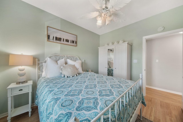 bedroom featuring a ceiling fan, lofted ceiling, baseboards, and wood finished floors