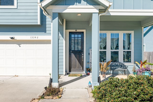 property entrance featuring an attached garage, driveway, a porch, and board and batten siding