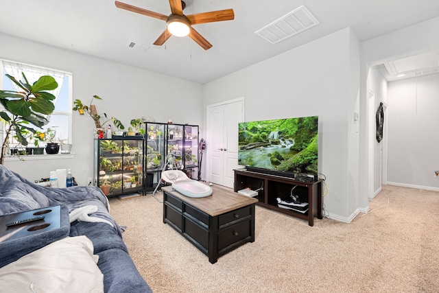 living area featuring attic access, baseboards, visible vents, a ceiling fan, and light colored carpet