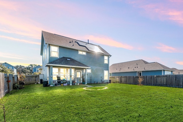 rear view of house with a fenced backyard and a yard