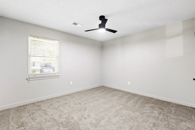 carpeted spare room featuring a textured ceiling, ceiling fan, visible vents, and baseboards