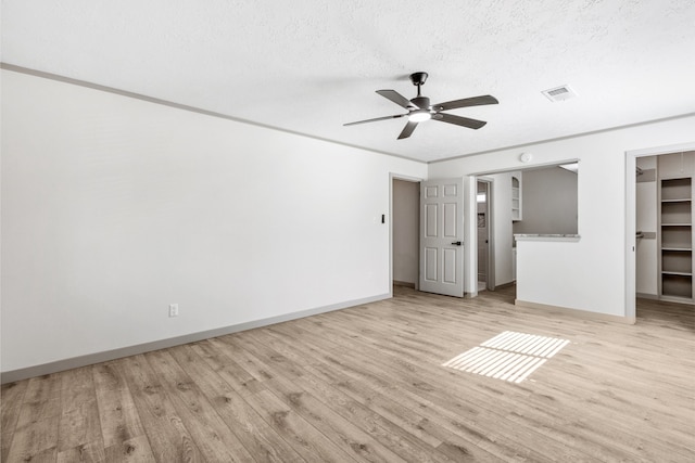 unfurnished bedroom with light wood-type flooring, a spacious closet, and visible vents