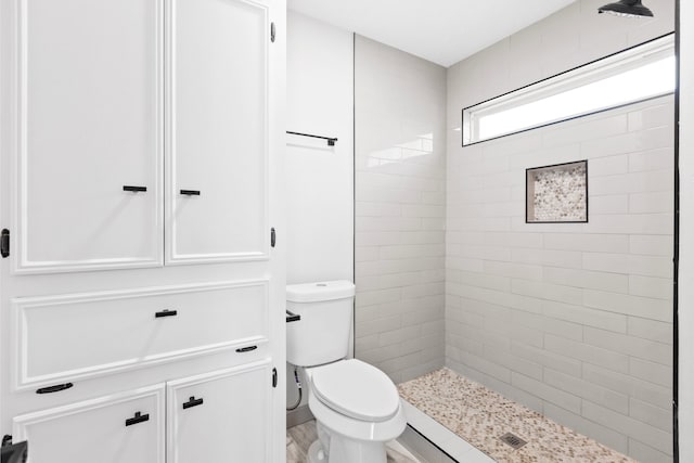 bathroom featuring tiled shower and toilet