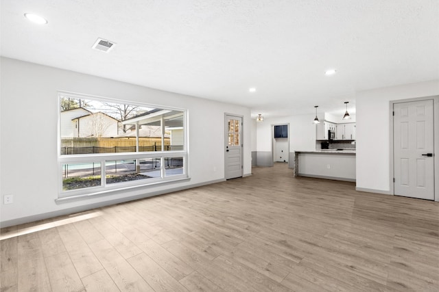 unfurnished living room featuring recessed lighting, light wood-type flooring, and baseboards