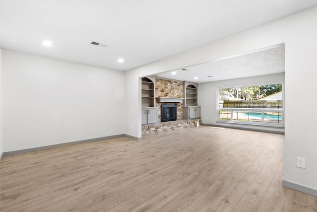 unfurnished living room featuring baseboards, a brick fireplace, and light wood-style floors