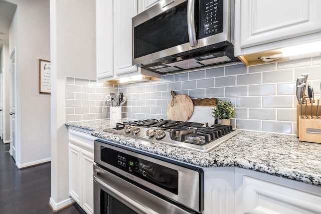 kitchen featuring dark wood-type flooring, light stone counters, tasteful backsplash, white cabinetry, and stainless steel appliances