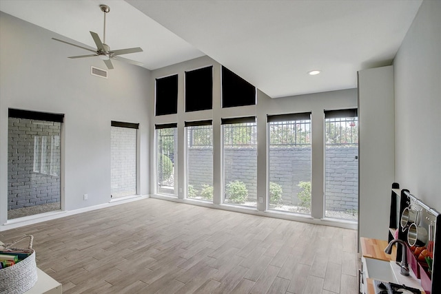 living area featuring a ceiling fan, visible vents, a high ceiling, and wood finished floors