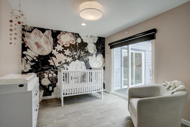 bedroom featuring access to outside, an accent wall, baseboards, and wood finished floors