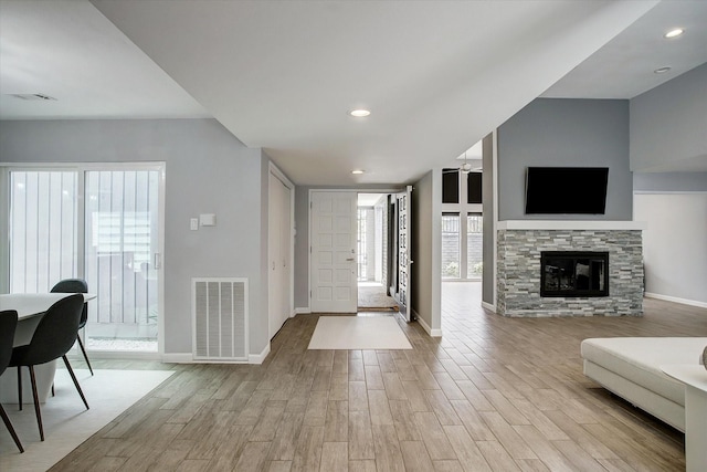 entryway featuring visible vents, a stone fireplace, baseboards, and wood finished floors