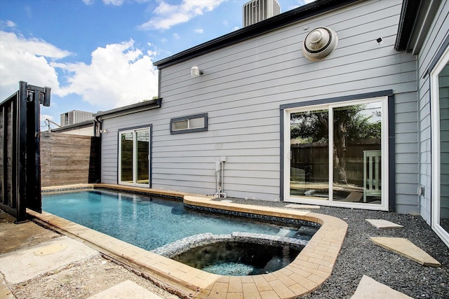 view of swimming pool featuring a patio area, a pool with connected hot tub, and fence