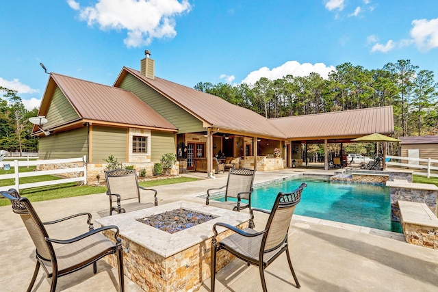 view of swimming pool with a patio area, a pool with connected hot tub, fence, and a fire pit