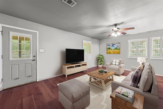 living room with a ceiling fan, visible vents, baseboards, and wood finished floors