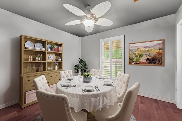 dining room with dark wood-type flooring, ceiling fan, and baseboards