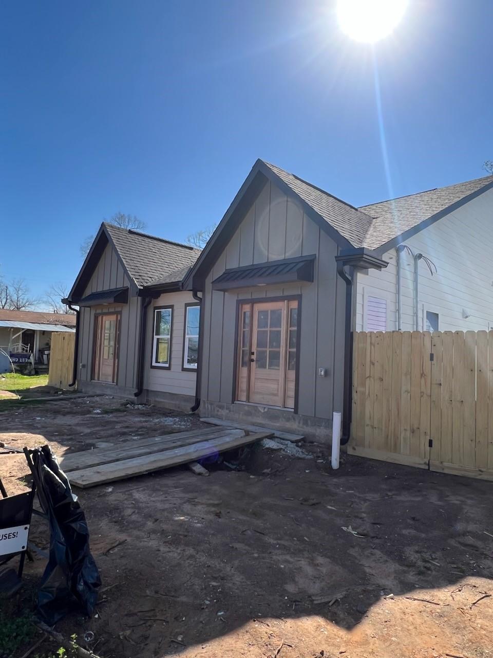 rear view of house with a shingled roof, board and batten siding, fence, and a wooden deck