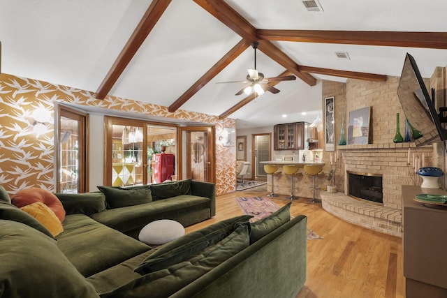 living room with light wood-type flooring, visible vents, a fireplace, and lofted ceiling with beams