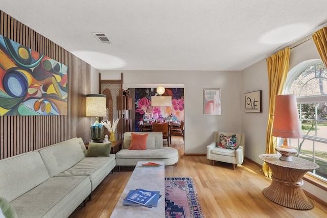 living area featuring baseboards, visible vents, and wood finished floors