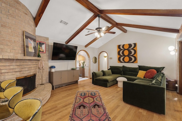 living area with lofted ceiling with beams, a fireplace, visible vents, and wood finished floors