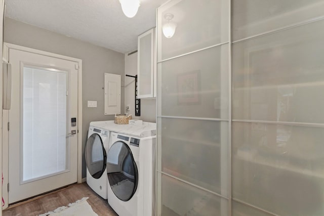 washroom with a textured ceiling, wood finished floors, laundry area, electric panel, and independent washer and dryer