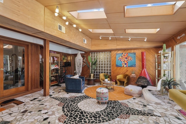 living area featuring a skylight, wooden walls, and visible vents