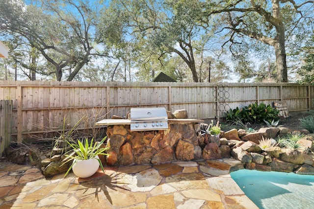 view of patio with exterior kitchen, grilling area, and a fenced backyard