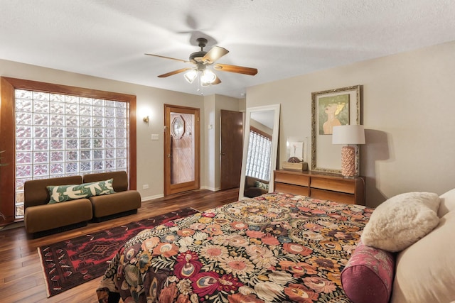 bedroom with a ceiling fan, a textured ceiling, baseboards, and wood finished floors