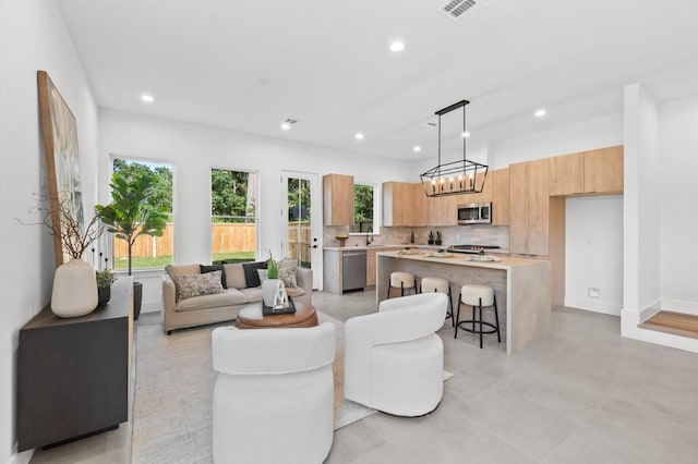 living room with baseboards, visible vents, and recessed lighting