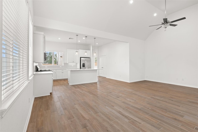 unfurnished living room featuring baseboards, ceiling fan, vaulted ceiling, light wood-style floors, and recessed lighting