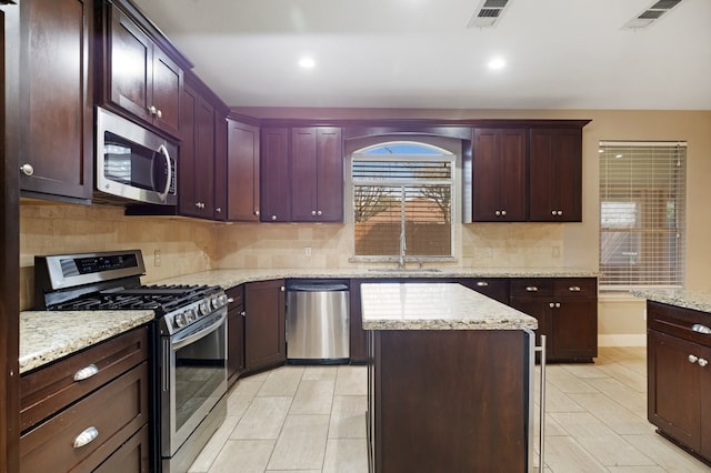 kitchen with appliances with stainless steel finishes, a sink, visible vents, and a center island