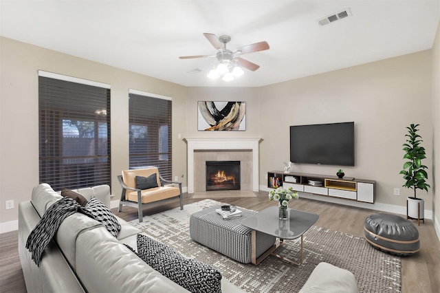 living area with a ceiling fan, visible vents, baseboards, and wood finished floors