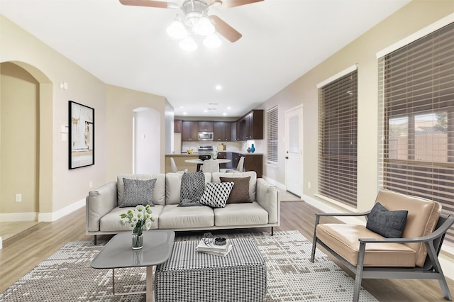 living area featuring arched walkways, light wood finished floors, recessed lighting, and baseboards