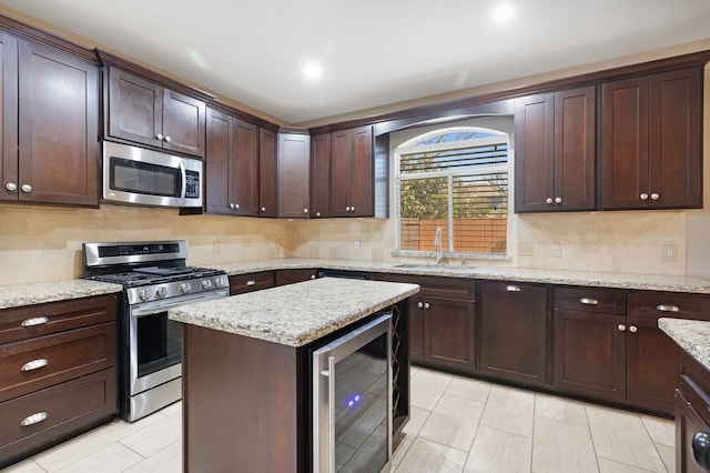 kitchen featuring wine cooler, stainless steel appliances, decorative backsplash, a sink, and dark brown cabinets