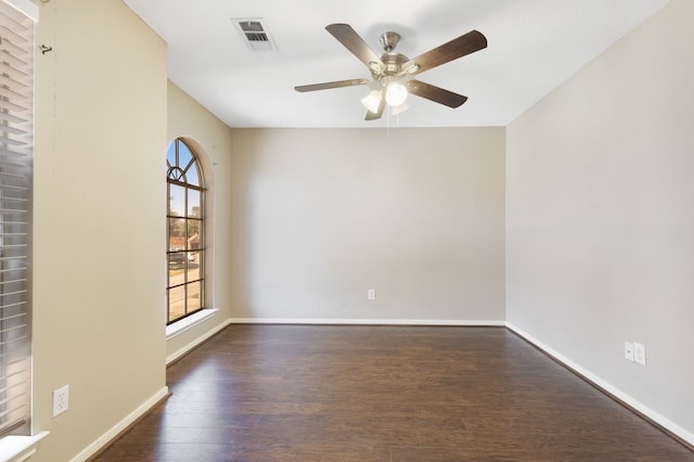 unfurnished room featuring dark wood-type flooring, a ceiling fan, visible vents, and baseboards