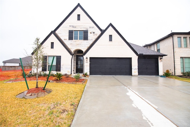 view of front of home featuring a front yard, stone siding, driveway, and an attached garage