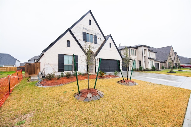 view of front of property with a residential view, fence, concrete driveway, and a front yard