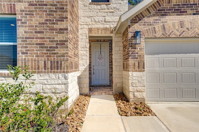 view of exterior entry featuring an attached garage, stone siding, and brick siding