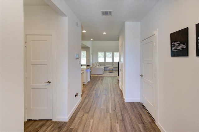 corridor with recessed lighting, visible vents, baseboards, and wood finished floors