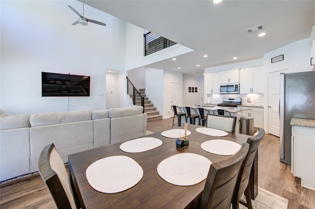 dining space featuring light wood-type flooring, stairs, visible vents, and recessed lighting