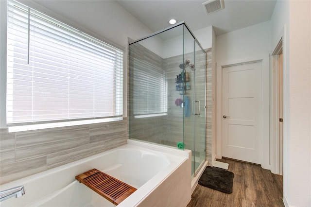 bathroom featuring wood finished floors, a stall shower, a garden tub, and visible vents