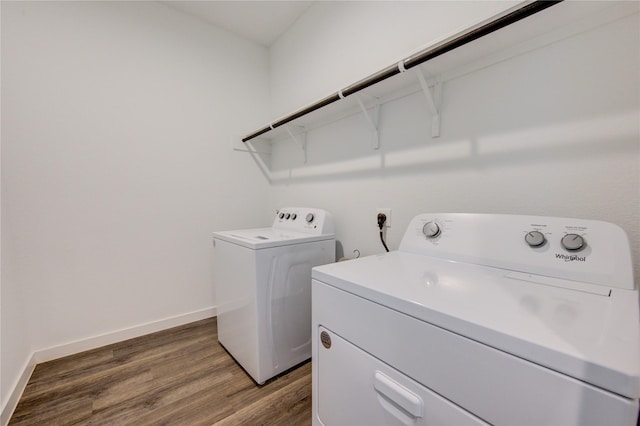 washroom with laundry area, washer and clothes dryer, wood finished floors, and baseboards