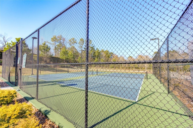 view of tennis court featuring community basketball court and fence