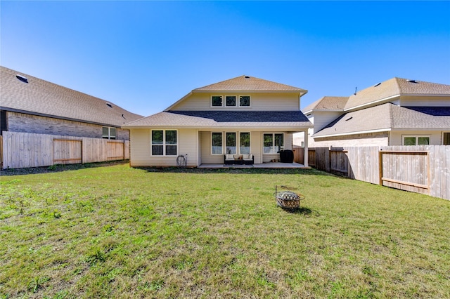 back of property with a fenced backyard, a lawn, a fire pit, and a patio